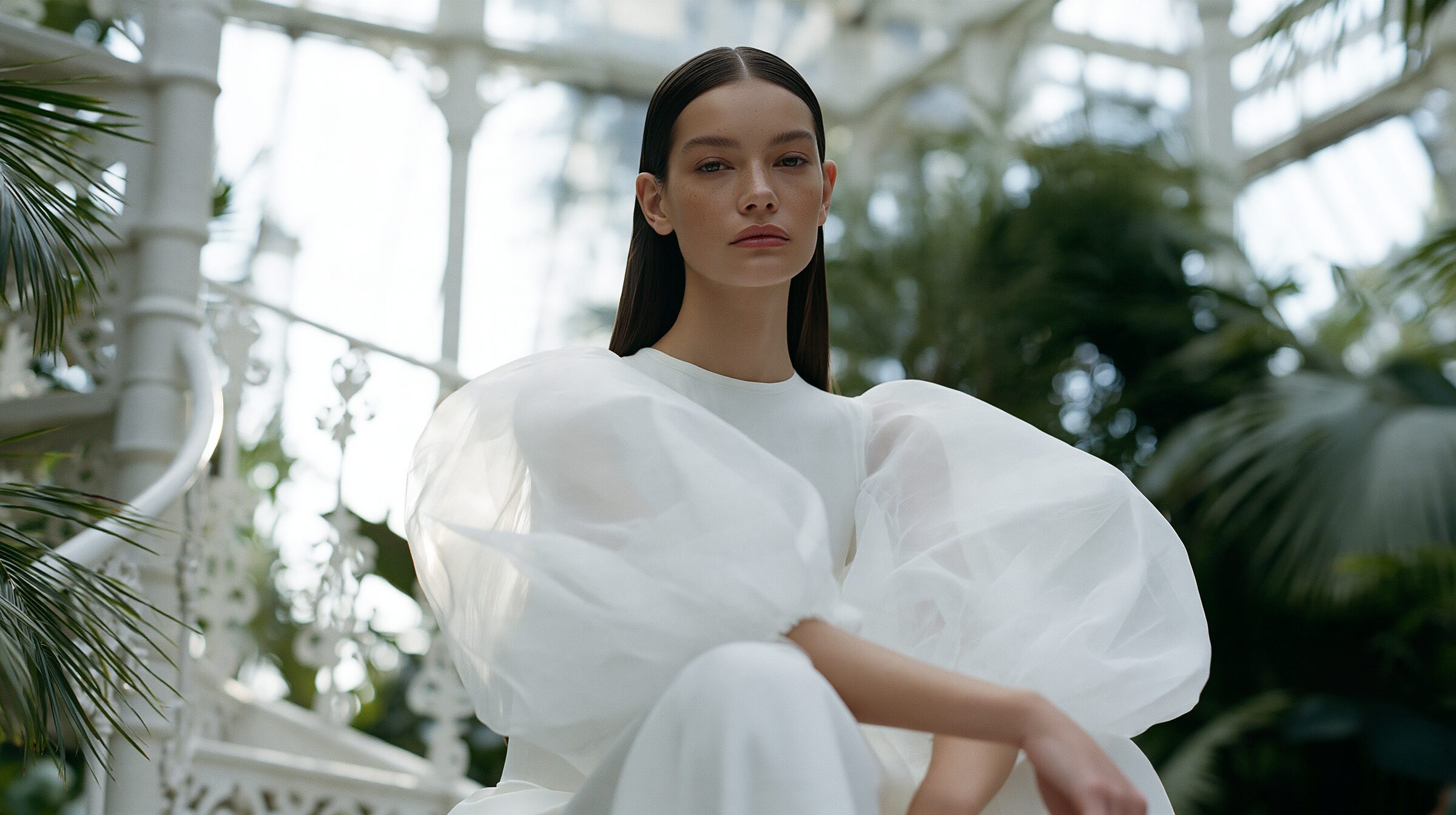 Model in an ivory organza gown seated on a white spiral iron staircase at golden hour