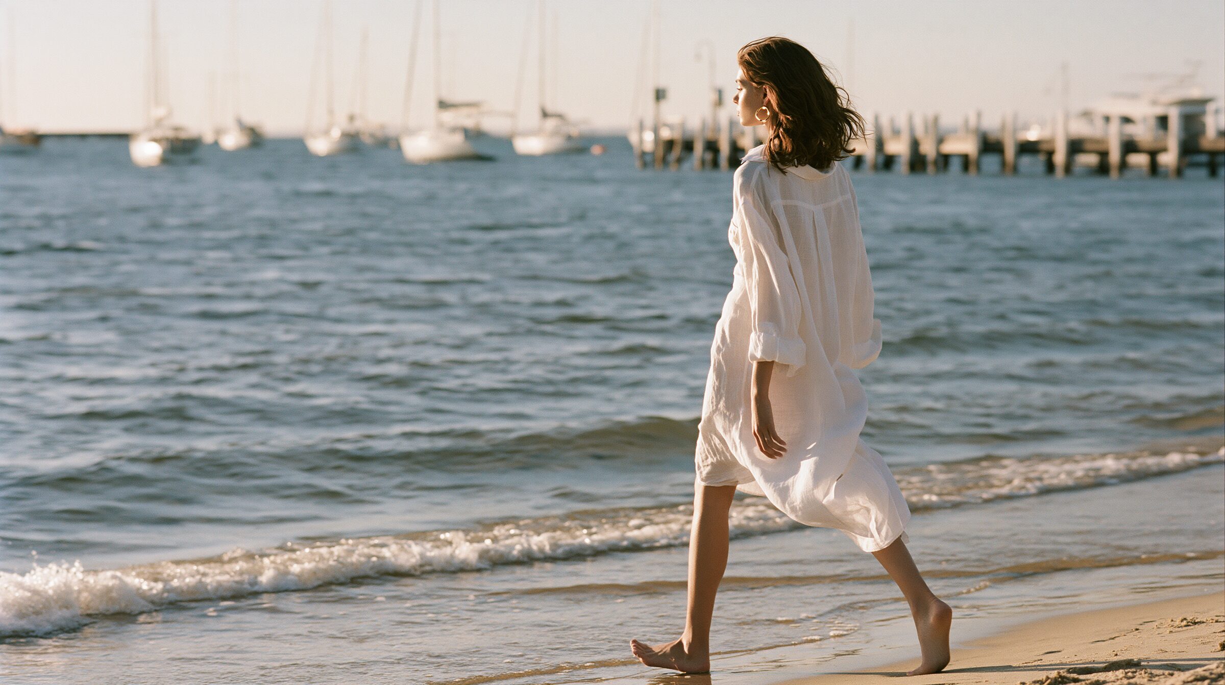Model walking barefoot along the water's edge