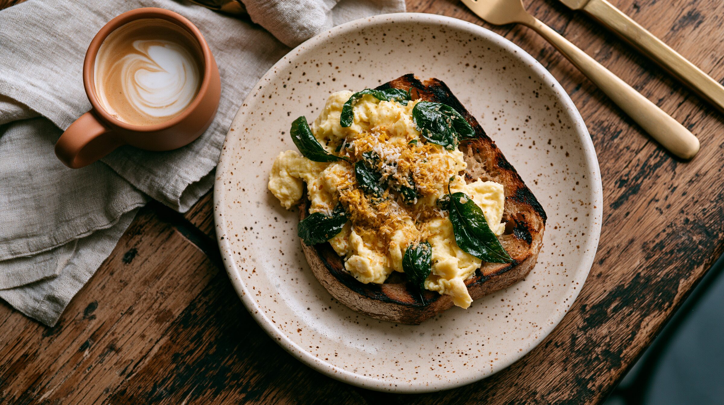 Flat lay of scrambled eggs with coconut sambol, curry leaves and charred sourdough